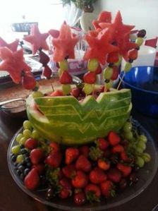 This watermelon is shaped like Wonder Woman's symbol. And many fruits are on skewers with watermelon stars.