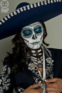 This woman wears a sombrero that matches her outfit and makeup. And she has it buttoned to show some of her ribs.